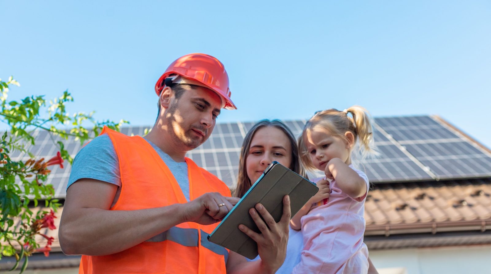 Técnico y familia ante una vivienda con placas solares